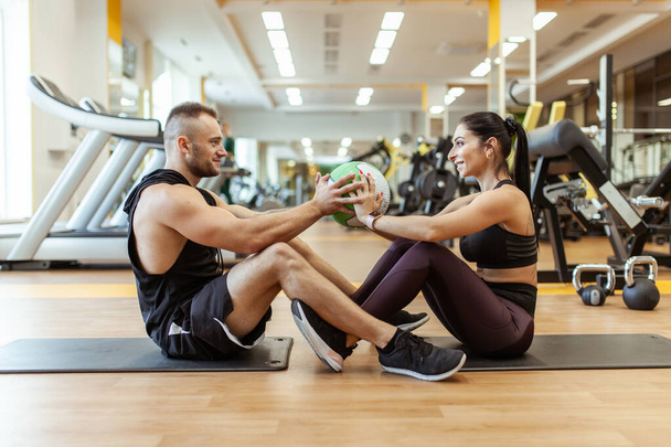 Athletic man and woman are training together with medicine ball in modern gym. Healthy lifestyle - Foto, afbeelding