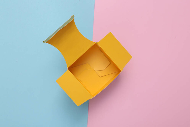 Желтая открытая коробка на сине-розовом фоне. Шаблон для макета. Вид сверху - Фото, изображение
