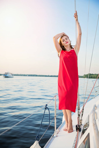 Beautiful woman relaxing on the nose of the yacht at a sunny summer day at the river and enjoying at happy holidays - Фото, зображення