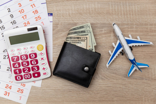 Paper Calendar with air plane, purse and calculator on table. Travel concept. Top view - Photo, image