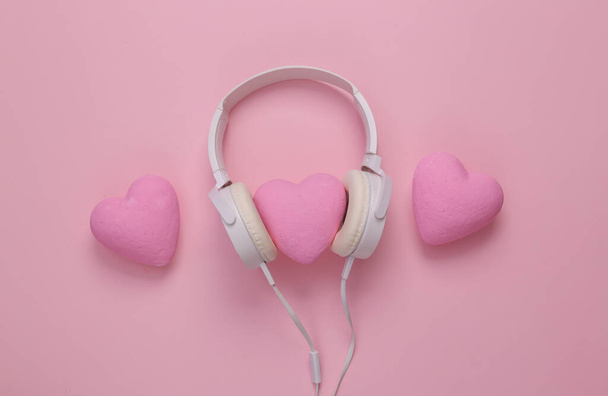 Headphones with hearts on a pink background. Romantic melody. Top view - Zdjęcie, obraz