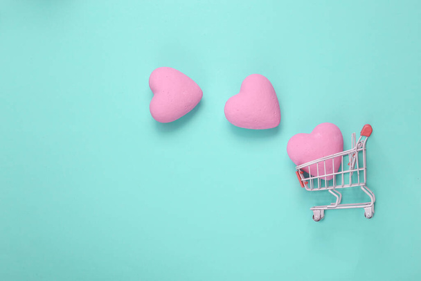 Shopping trolley with hearts on blue background. Love concept. Top view - Foto, afbeelding