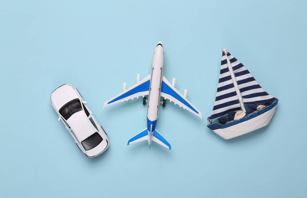 Toy Passenger plane, car and sailboat on blue background. Transport. Travel concept. Top view. Flat lay - Zdjęcie, obraz