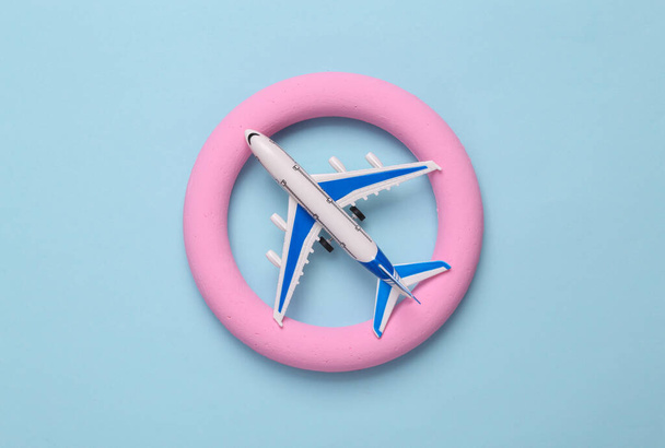 Passenger plane in a pink circle on a blue background. Minimal travel concept - Фото, изображение