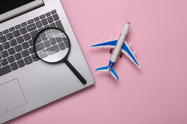 Travel concept. Passenger plane with laptop and magnifying glasses on pink background. Top view - Foto, Imagen