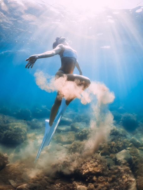 Freediver woman with sand in hands. Lady freediver with fins underwater in blue ocean - Photo, Image