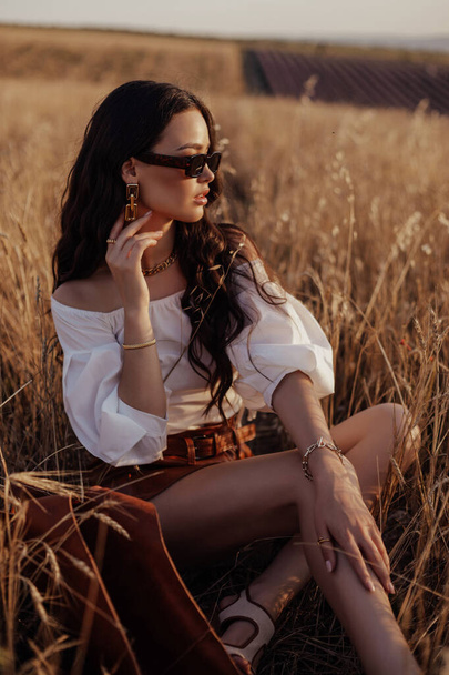 fashion outdoor photo of beautiful sexy woman with dark hair in casual clothes posing in summer sunset wheat field - Foto, Bild