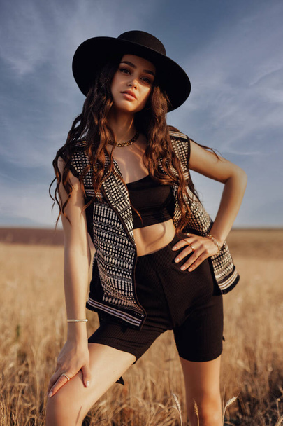 fashion outdoor photo of beautiful sexy woman with dark hair in casual clothes posing in summer sunset wheat field - Zdjęcie, obraz