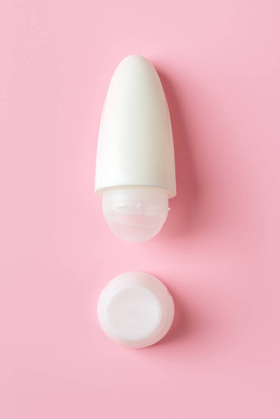 Roll on antiperspirant as the exclamation point shape on a pink background. Roll-on body deodorant in a white plastic tube. Hygiene and toiletries for reduce perspiration concept. Close-up. - Fotografie, Obrázek