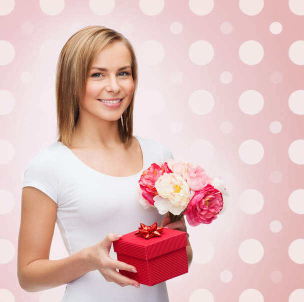 smiling young woman with gift box and flowers - Valokuva, kuva