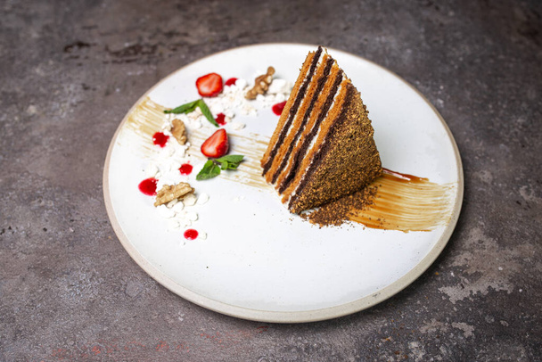 Delicious layered honey cake served on a white ceramic dessert plate. - Фото, зображення