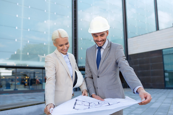 smiling businessmen with blueprint and helmets - Photo, image