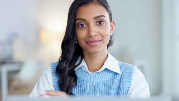 Confident and happy indian business woman feeling ambitious and motivated for success in a creative startup agency. Portrait of a young designer smiling while working on a laptop in a modern office - Кадры, видео