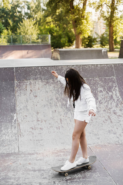 Dětská dívka jezdit na skateboardu na sportovní rampě. Sportovní vybavení pro děti. Aktivní teenager s skateboard na hřišti skate park - Fotografie, Obrázek