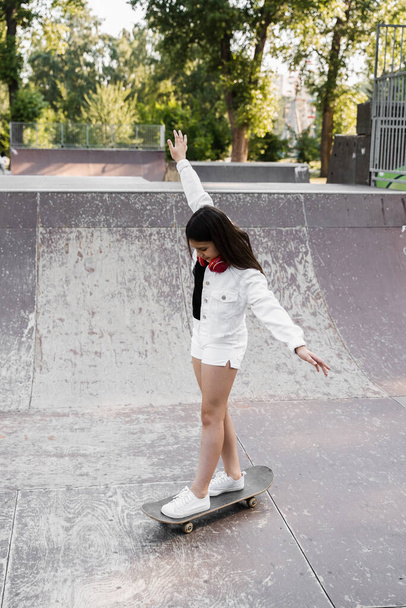 Child girl ride on skate board on sport ramp. Sports equipment for kids. Active teenager with skateboard on skate park playground - Valokuva, kuva