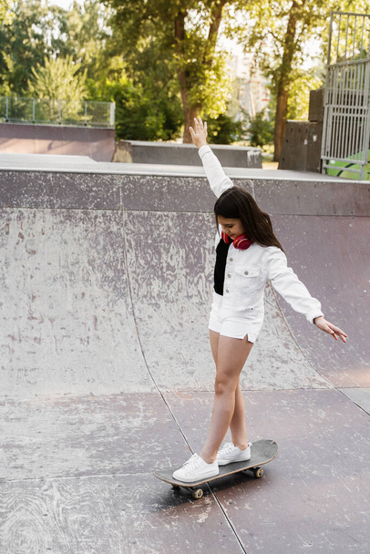 Child girl ride on skate board on sport ramp. Sports equipment for kids. Active teenager with skateboard on skate park playground - Φωτογραφία, εικόνα