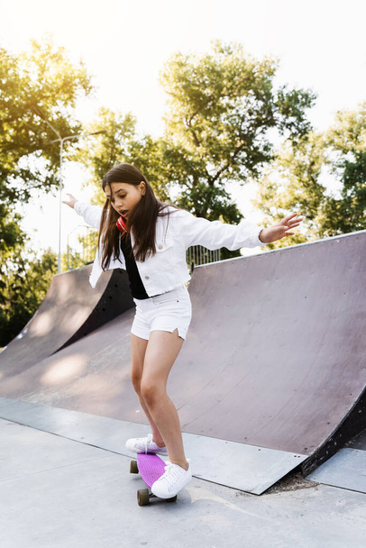 Shocked child girl before fall from penny board on skate park playground at sunset. Sports equipment for kids. Active teenager with pennyboard on skate park playground - Foto, Imagen
