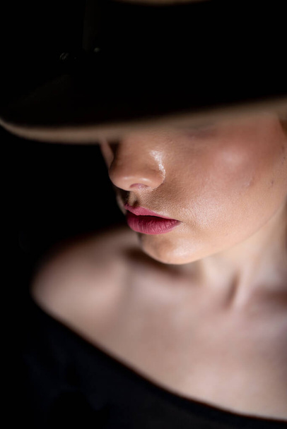 a stranger girl in a hat on a black background. - Фото, изображение