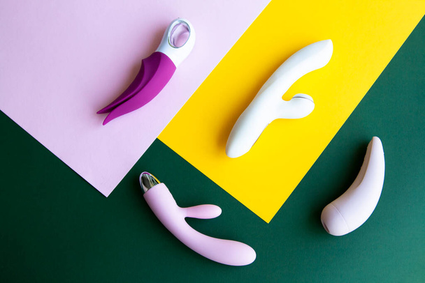 Collection of different types of sex toys on a pink, green and yellow background. Sex toys for adults, dildos, vibrators, clitoral stimulators. - Φωτογραφία, εικόνα