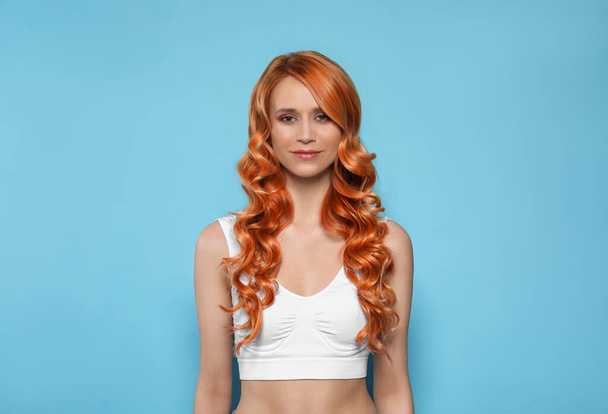 Beautiful woman with long orange hair on light blue background - Fotografie, Obrázek