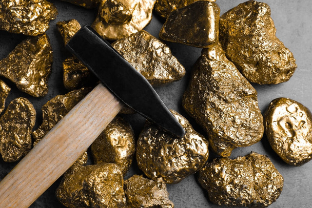 Gold nuggets and hammer on grey table, flat lay - 写真・画像