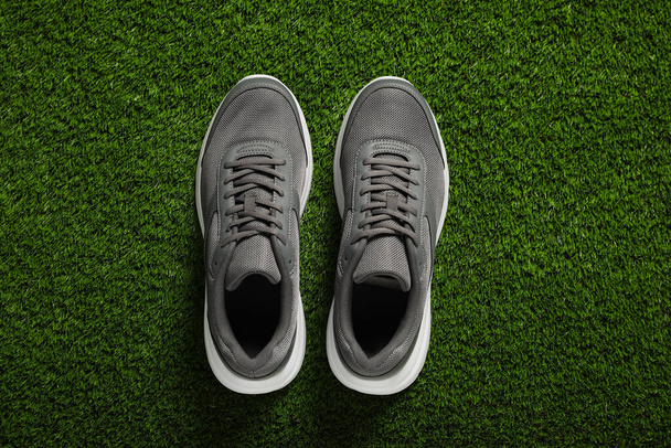 Pair of stylish sport shoes on green grass, flat lay - Foto, Bild