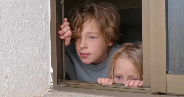 Boy and girl looking out of the open house window. Elder brother showing something interesting to the sister - Video