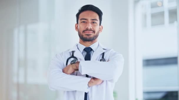 One medical professional looking proud and confident after completing a surgery. Portrait of a male doctor laughing and smiling while standing with arms crossed at a hospital alone - Imágenes, Vídeo