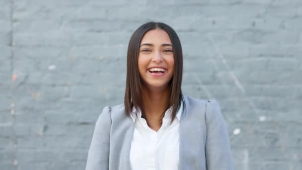 Cheerful woman laughing and giggling about something funny while standing outside against a grey wall with copy space. Happy businesswoman having fun and expressing positivity and a playful attitude. - Imágenes, Vídeo
