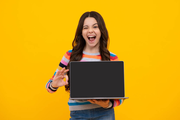 Amazed teenager. Student school girl with laptop on isolated studio background. Screen of laptop computer with copyspace mockup. Excited teen schoolgirl - Foto, Imagem