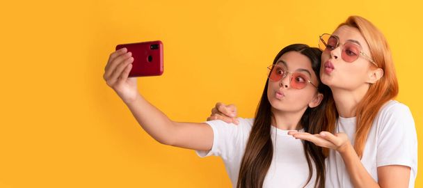 Mother and daughter child banner, copy space, isolated background. happy woman and girl take selfie with smartphone. selfie family. modern life - Fotó, kép