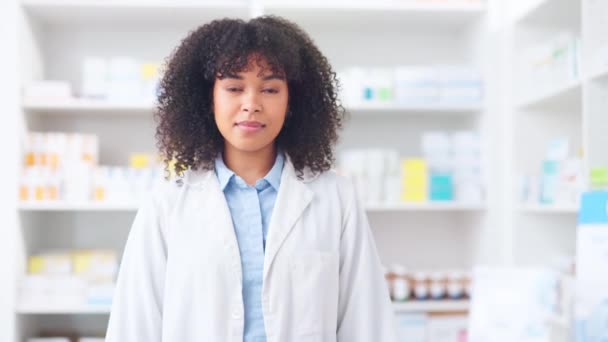 Een trotse apotheker die voor medicijnplanken staat in een apotheek. Jonge vrouwelijke zorgverlener staat met haar armen gekruist, draagt een labjas en glimlacht in een apotheek. - Video