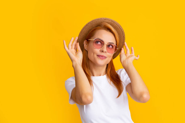 Portrét legrační ženy ve stylových slunečních brýlích a slamáku na žlutém pozadí - Fotografie, Obrázek