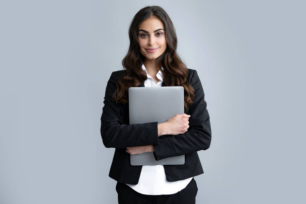 Χαρούμενη επιχειρηματίας στέκεται πάνω από γκρίζο τοίχο με φορητό υπολογιστή. Πορτρέτο της όμορφης, γοητευτικής, κομψής, έξυπνης γυναίκας με φορητό υπολογιστή απομονωμένο σε γκρι φόντο - Φωτογραφία, εικόνα