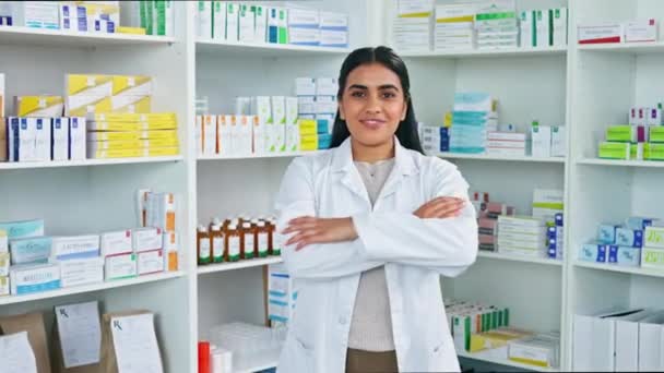 Portrait of female pharmacist in a pharmacy. One medical professional standing alone in drug store dispensary with many boxes of pills and tablets on shelves. Confident woman working with medication. - Imágenes, Vídeo