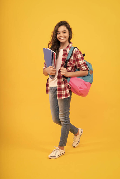 Boldog lány vissza az iskolába könyv és hátizsák sárga háttér, iskola. - Fotó, kép