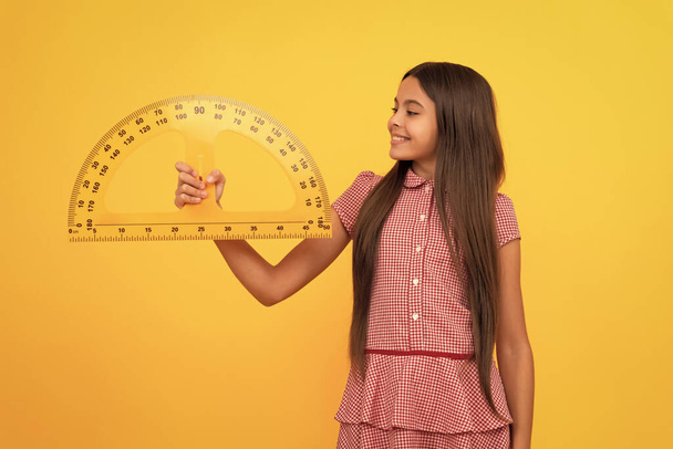 trigonometry stationery. measuring and sizing. education for child. mathematics. happy teen girl hold protractor ruler. back to school. algebra and geometry. kid study math. measure the size. - Foto, Imagen