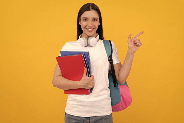 コピースペースで黄色のbにノートを持って幸せな女の子。コピーとヘッドフォン付きの私立教師です。学校に戻って。現代教育の概念です。学生手帳指差す指. - 写真・画像
