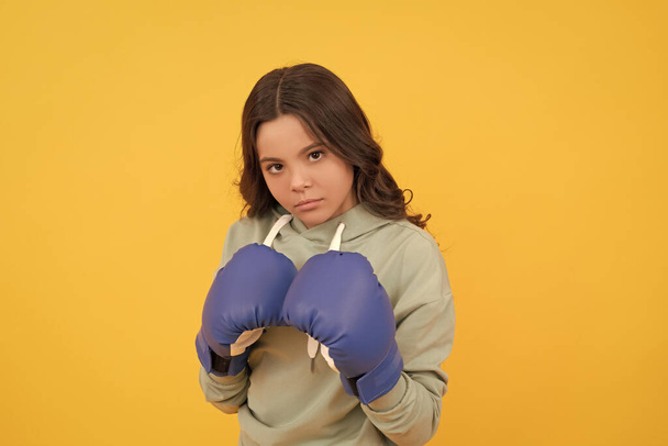 ernstes Kinderporträt in Boxhandschuhen auf gelbem Hintergrund. - Foto, Bild