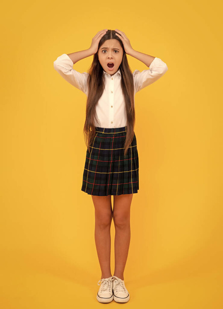 september 1. childhood. scared child. full length. worried teen girl touch her head. back to school. knowledge day. education concept. kid in uniform on yellow background. - Foto, Imagem