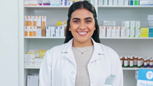 A smiling doctor working behind the pharmacy counter of a clinic or hospital. A friendly pharmacist laughing while standing in front of shelves of medicine, ready to advise patients or sell medicine - Video, Çekim