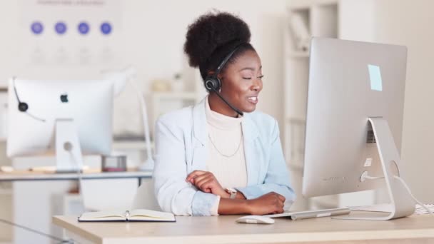 A confident lady working in sales at a call centre company. A smiling African American female talking a client on the phone, using a headset. Customer service agent doing a sales pitch via computer - Materiał filmowy, wideo