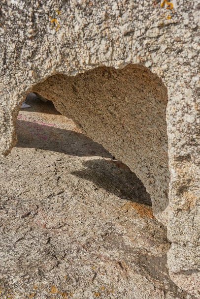 Closeup of rough rock with deep cracks, holes and crevices from wind, heat or water erosion from global warming or climate change. Texture detail and background of sedimentary rock or granite outside. - Fotoğraf, Görsel