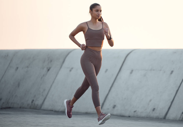Everybody gets better if they keep at it. a sporty young woman running outdoors - Фото, изображение