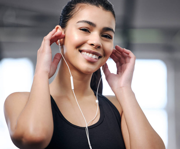 Sweat your way to a beautiful day. Portrait of a fit young woman using earphones at the gym - Fotografie, Obrázek