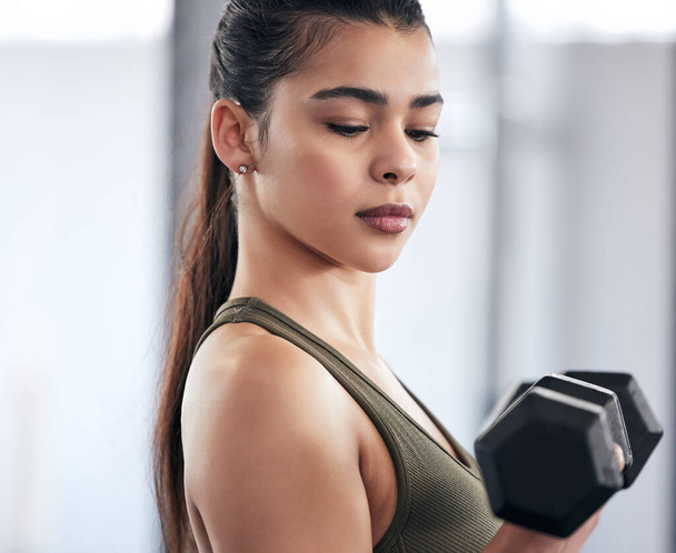 Mind over matter. a young woman working out with dumbbell weights in a gym - Photo, image