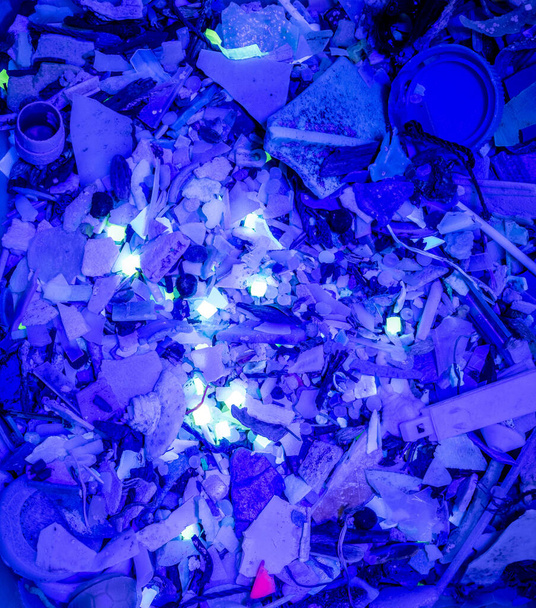 Микропластиковые отходы светятся под ультрафиолетовым светом. - Фото, изображение