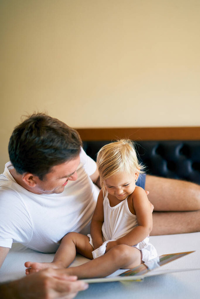 Laughing dad and little girl reading a book. High quality photo - Foto, imagen