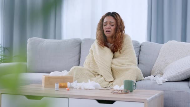 Chora kobieta kichająca i cierpiąca na przeziębienie lub grypę siedząc na kanapie w domu. Jedna chora i zmęczona młoda kobieta dmucha w nos i dochodzi do siebie po przebywaniu w kwarantannie w swoim mieszkaniu.. - Materiał filmowy, wideo