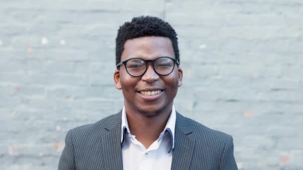 A cheerful African American advocate preparing to go into court for a case in town. Portrait of a happy male lawyer smiling while standing against a white wall outside in the city alone - Filmagem, Vídeo